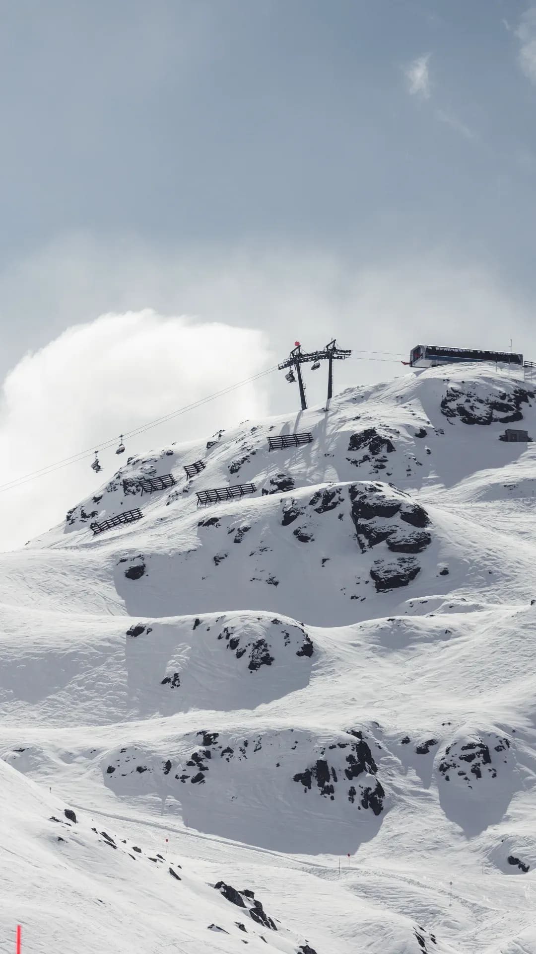 Verschneite Kuppe mit Liftstation, Schneewehe im Vordergrund