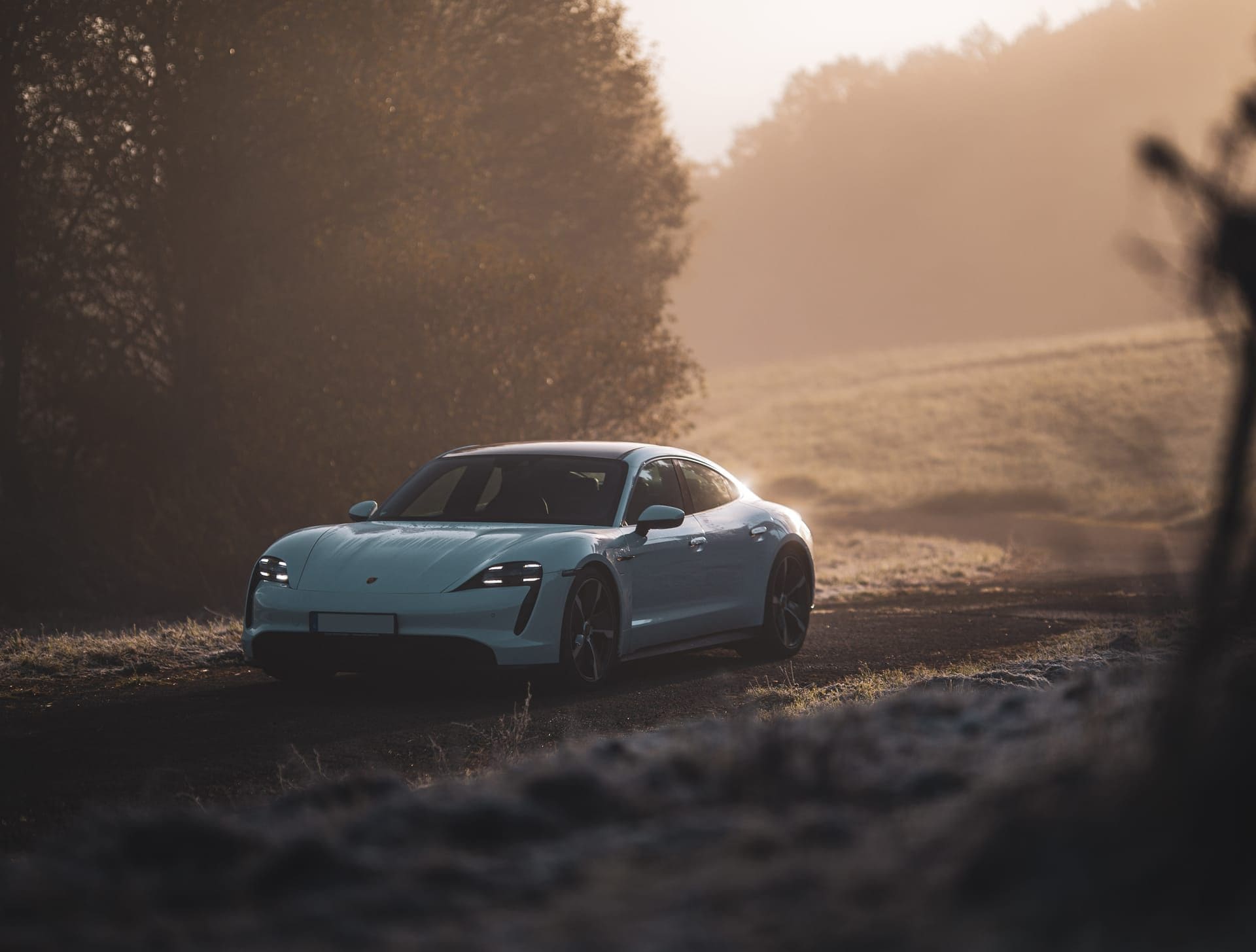 Heller Sportwagen im Morgennebel auf einem Feldweg, Dreiviertelansicht von vorn