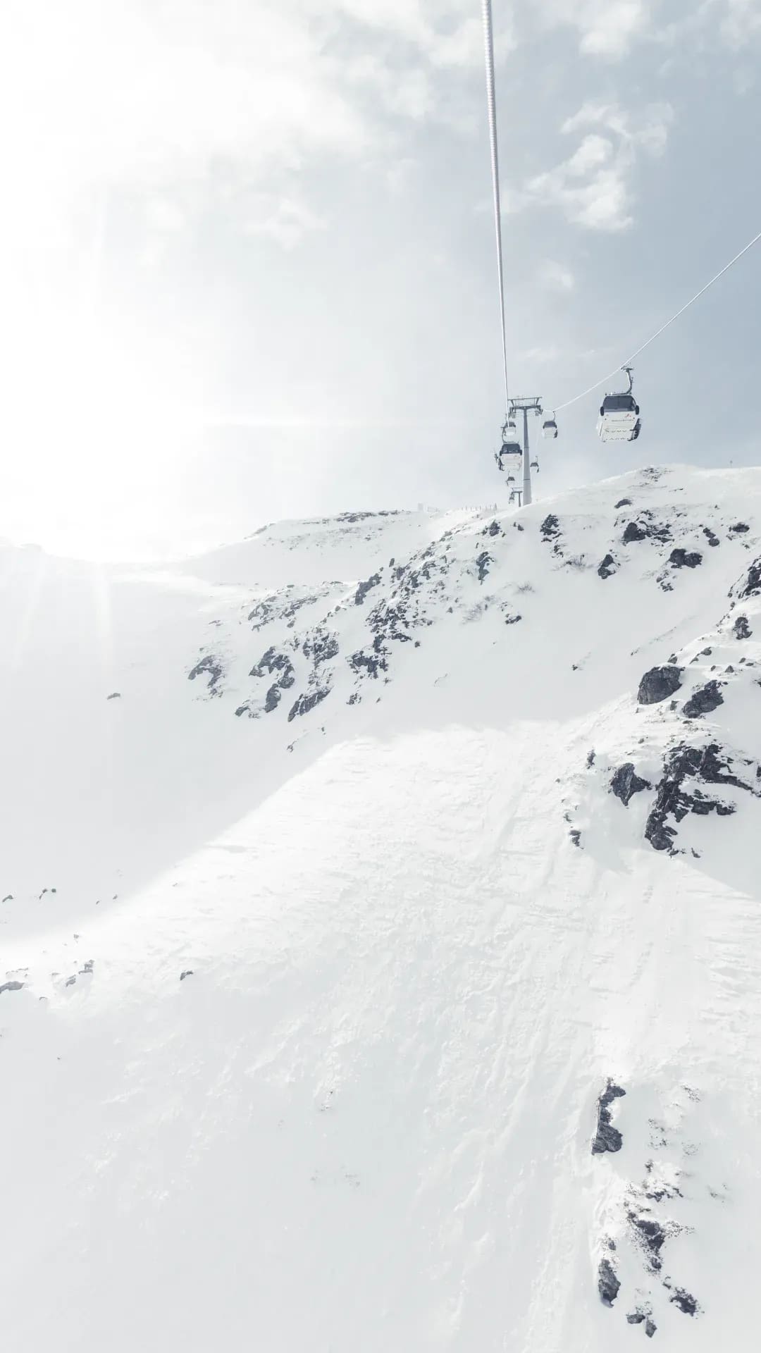 Gondelbahn im Gegenlicht über einem felsigen Grat