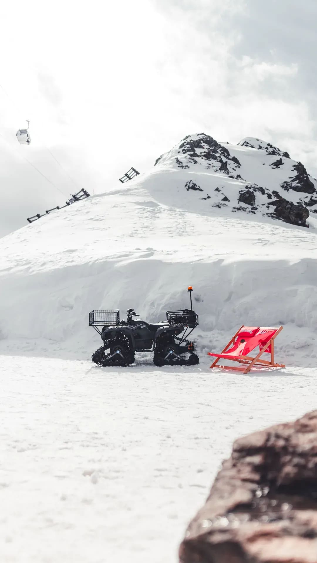 Quad und roter Liegestuhl neben einer Schneewechte