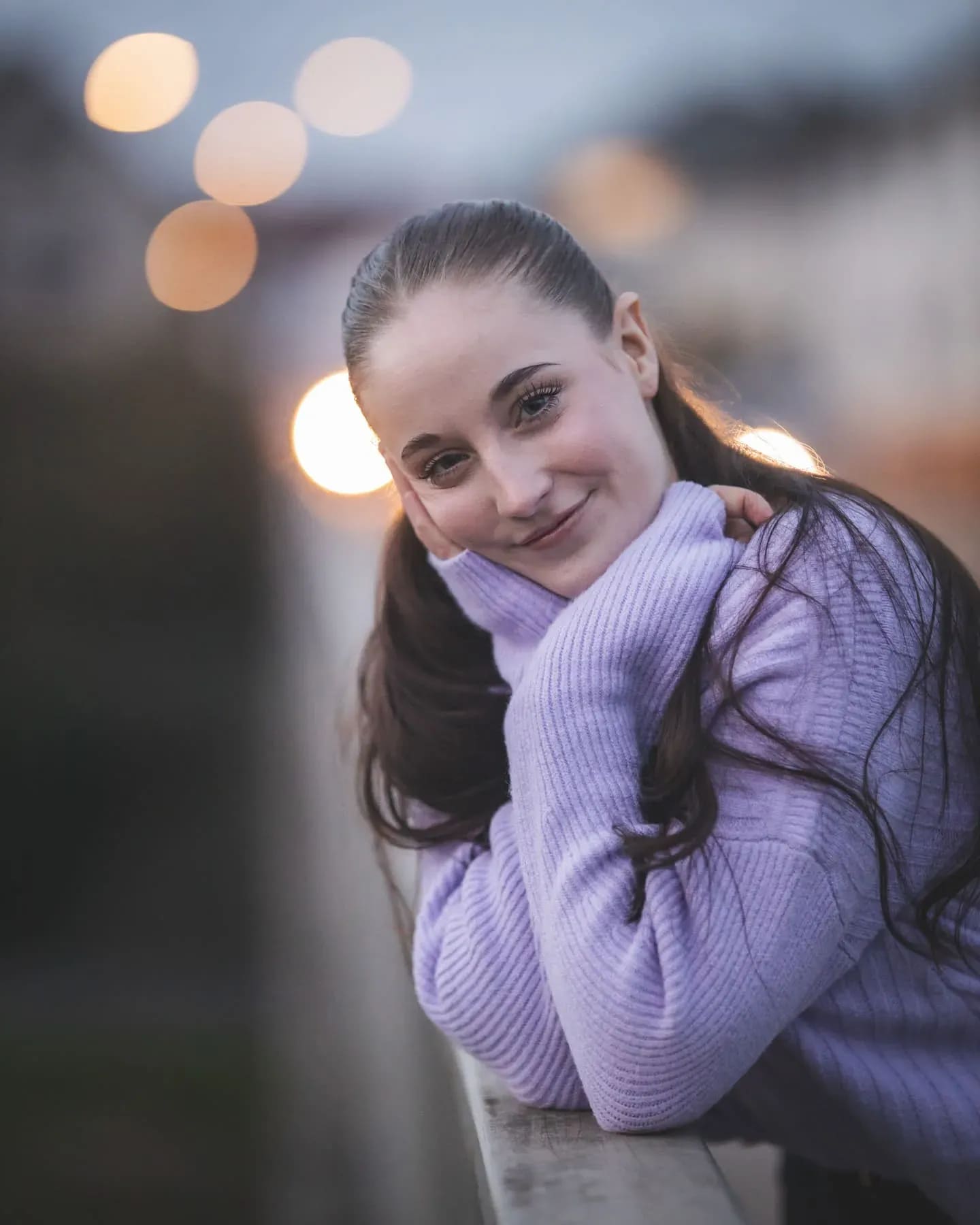 Junge Frau im lila Pullover, Lichtpunkte der Stadt im Hintergrund