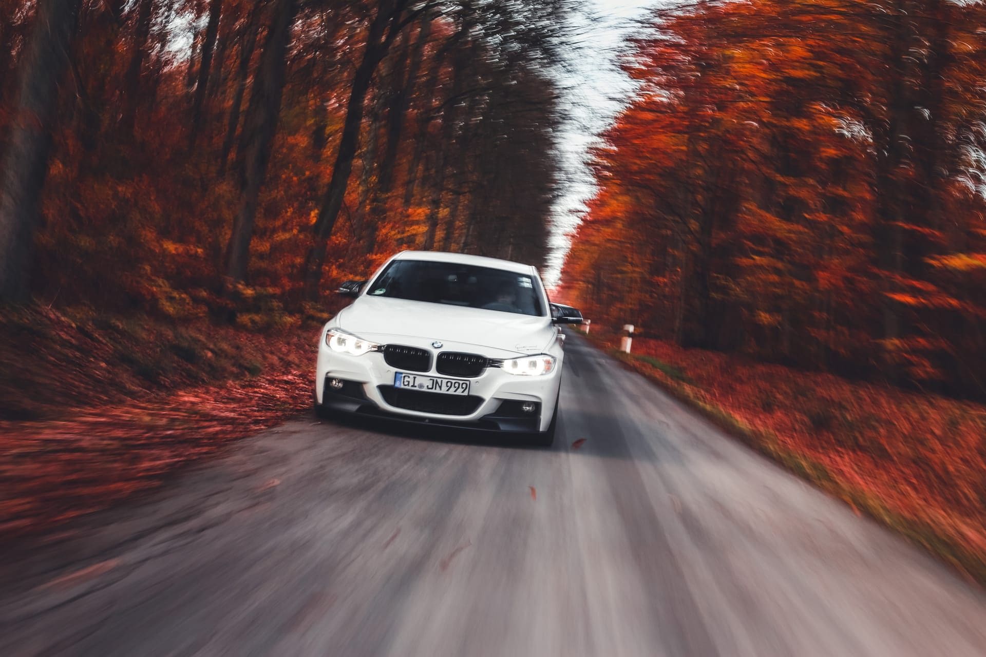 Dieselbe Limousine in Fahrt, Straße und Wald verwischen durch die lange Belichtung