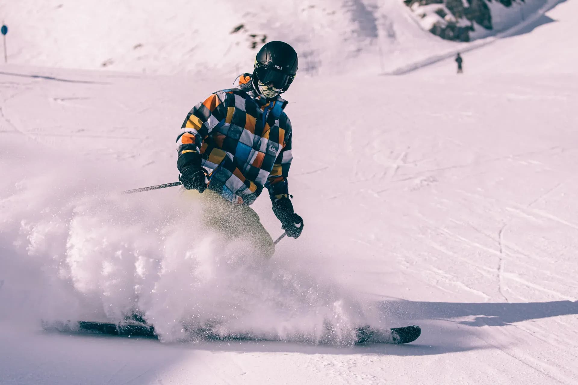 Skifahrer zieht einen Schwung, der Schnee staubt auf