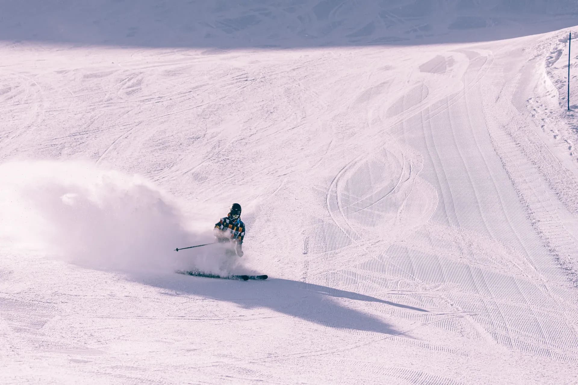 Einzelner Skifahrer auf einer weiten, frisch präparierten Piste