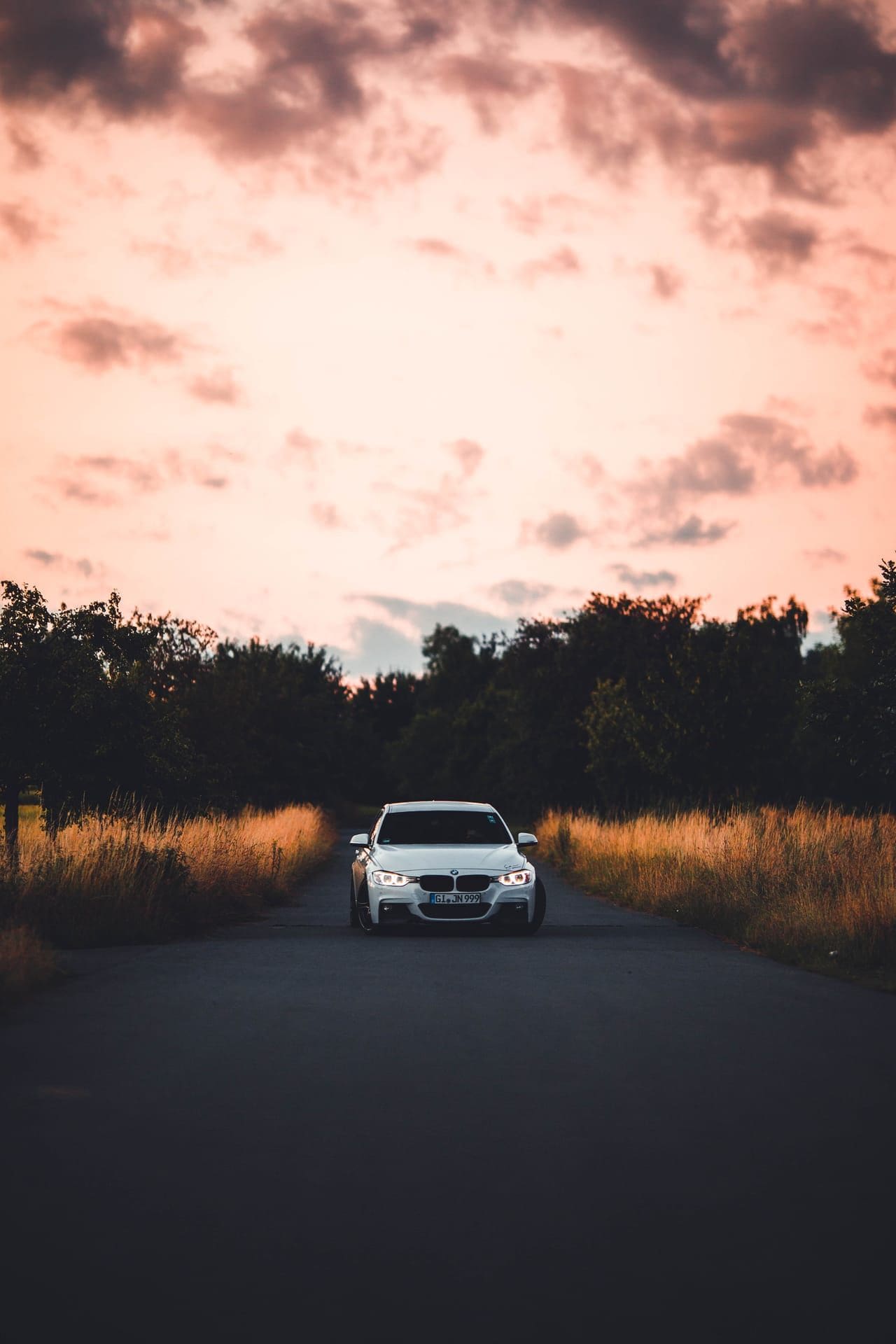 Limousine klein am Ende einer Landstraße unter rosa gefärbten Abendwolken