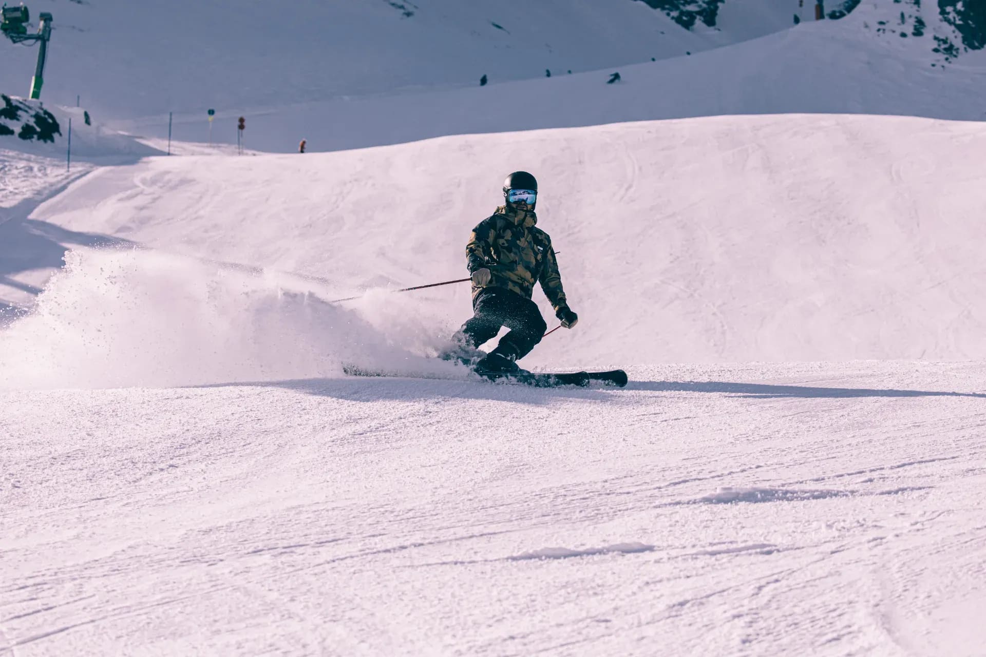 Skifahrer in der Kurve vor einem verschneiten Hügelrücken