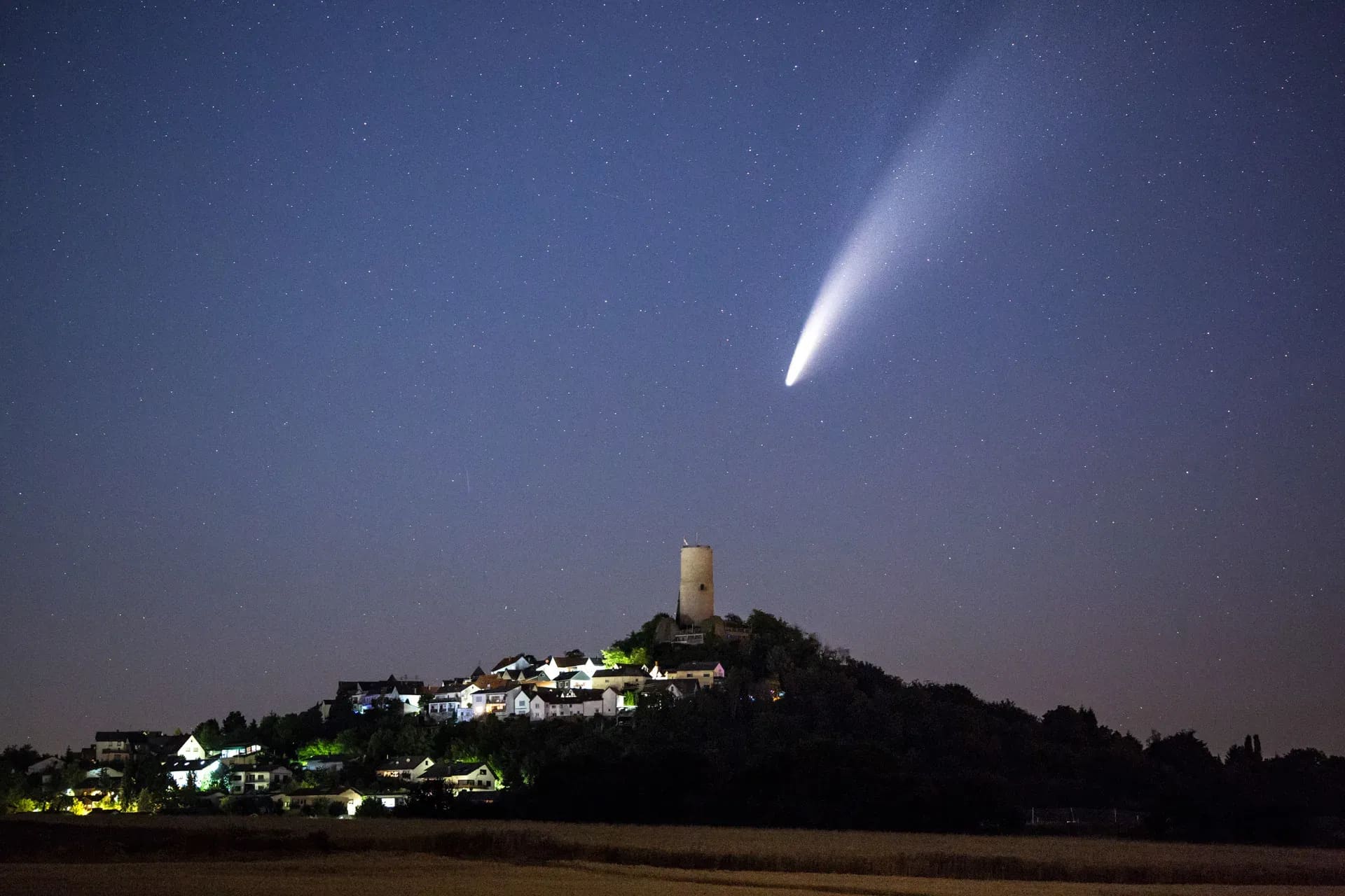 Komet Neowise über einem beleuchteten Burgberg