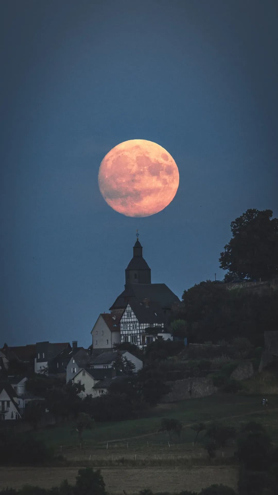 Vollmond über einer Kirche auf dem Hügel