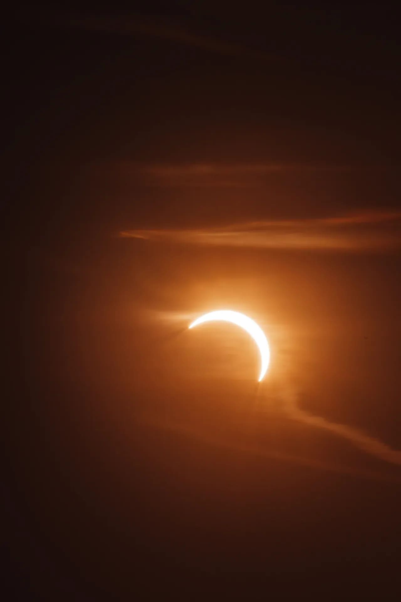 Sonnenfinsternis als schmale Sichel hinter Wolken