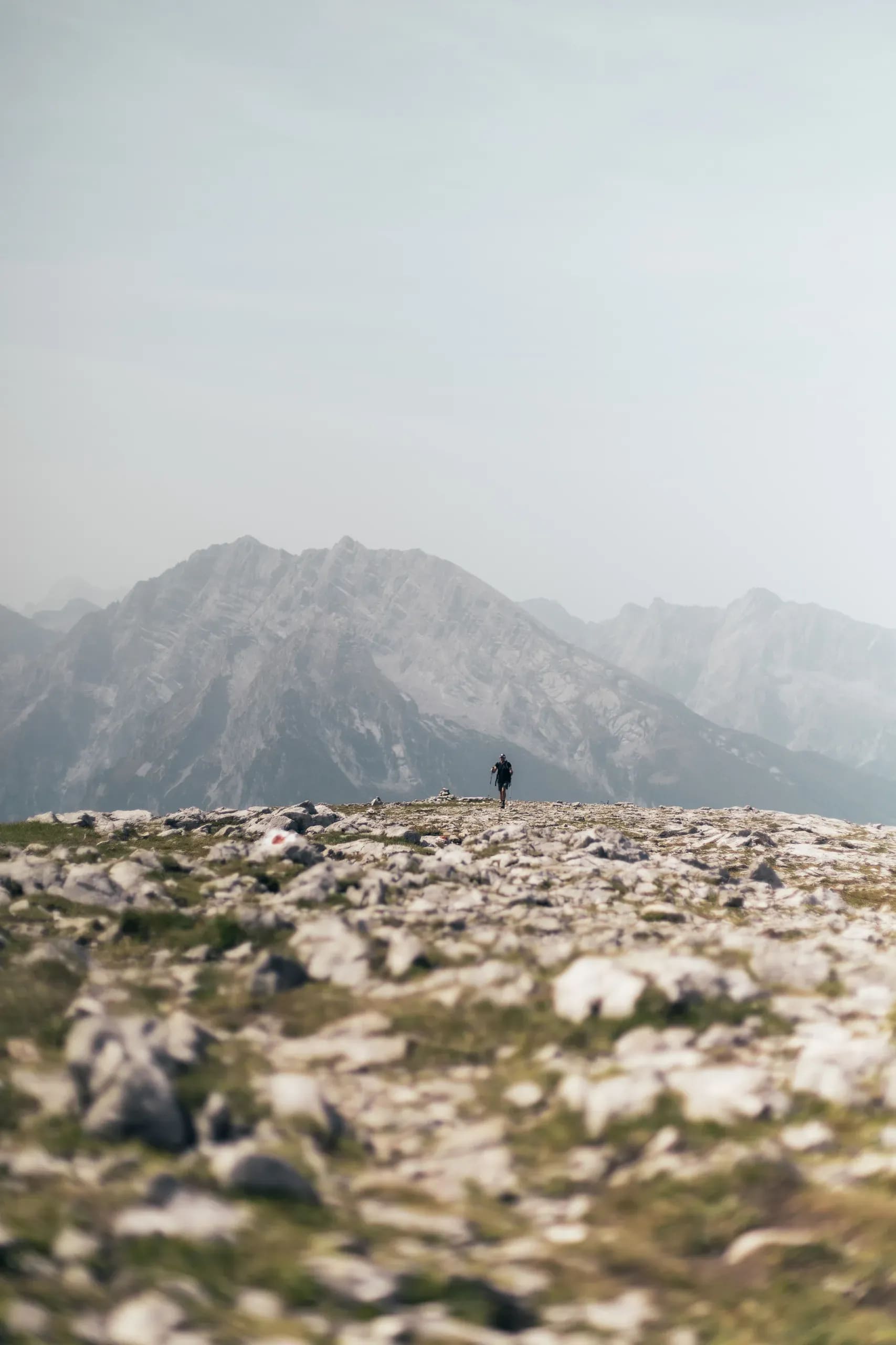 Wanderer auf einem Steinplateau, Gipfelkette dahinter