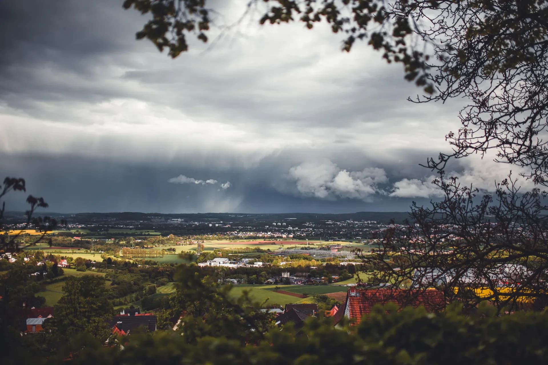 Regenschleier über dem Tal unter dunkler Wolkendecke