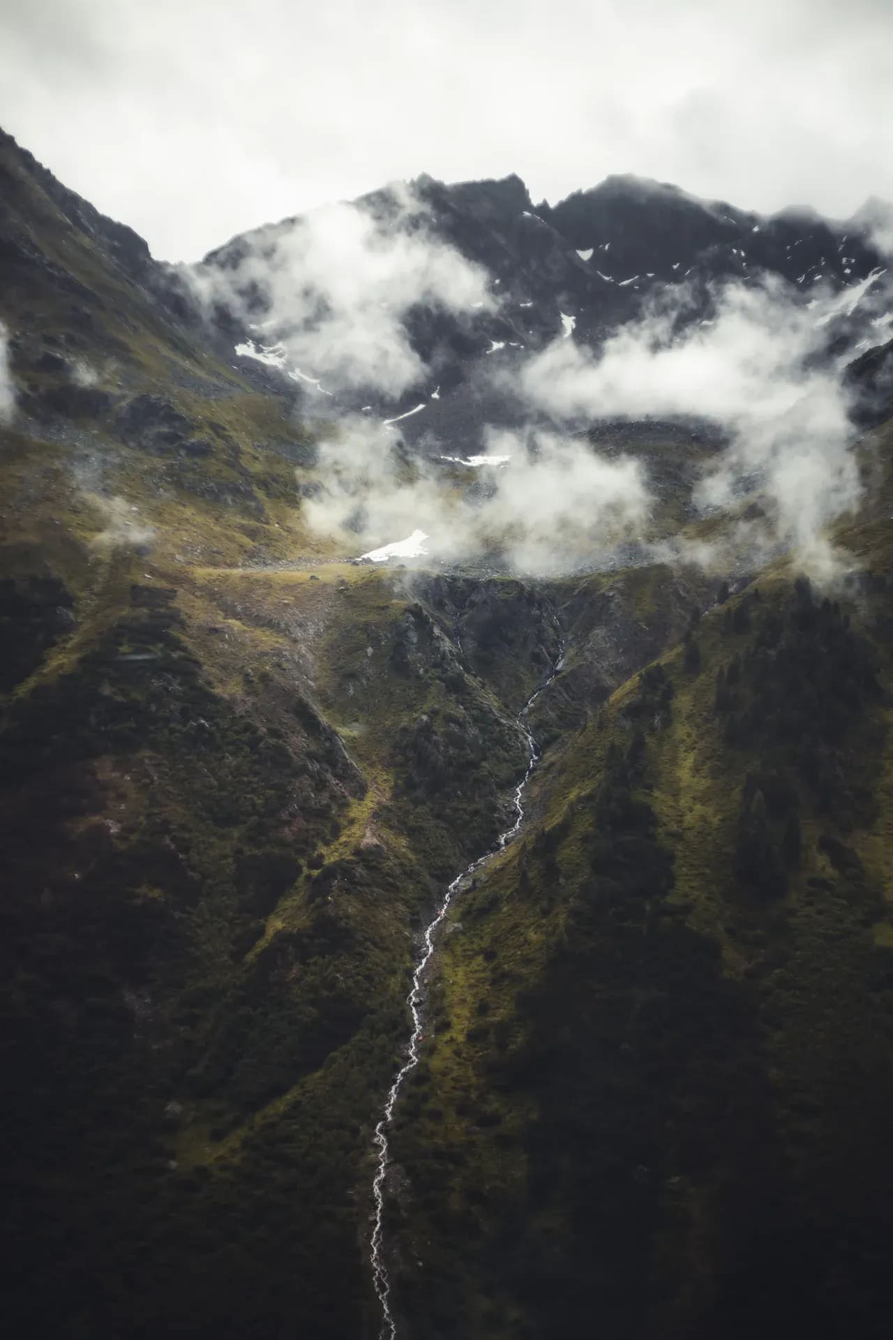Wasserfall an einer steilen Bergflanke in Wolken