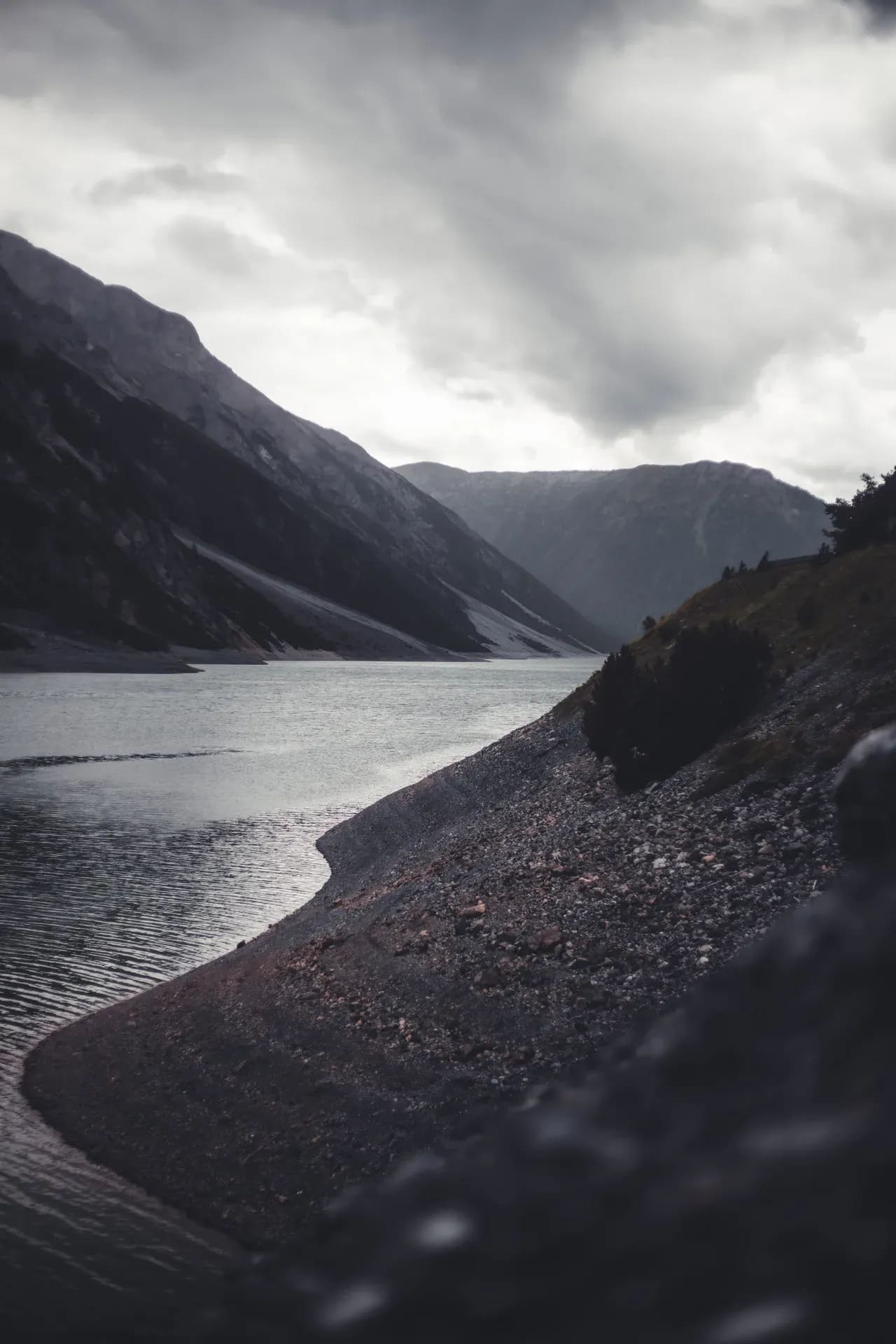 Stausee mit Staumauer unter grauem Himmel