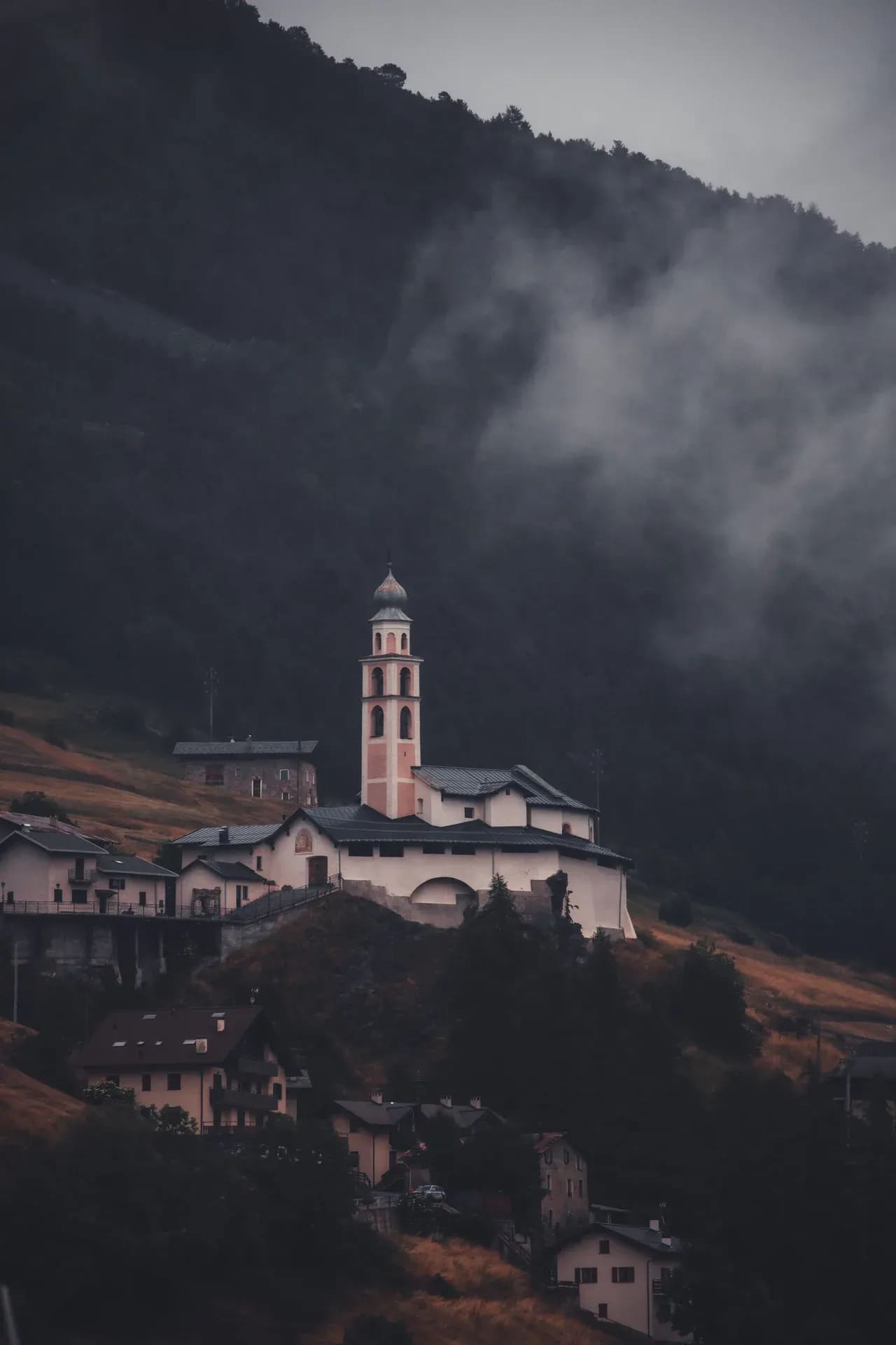 Kirche eines Bergdorfs unter Nebelschwaden