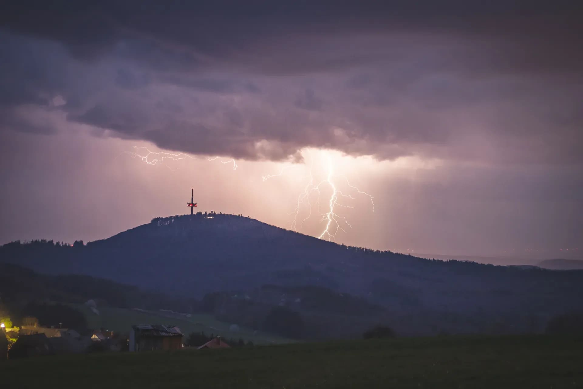 Blitz neben einem Hügel mit Sendemast