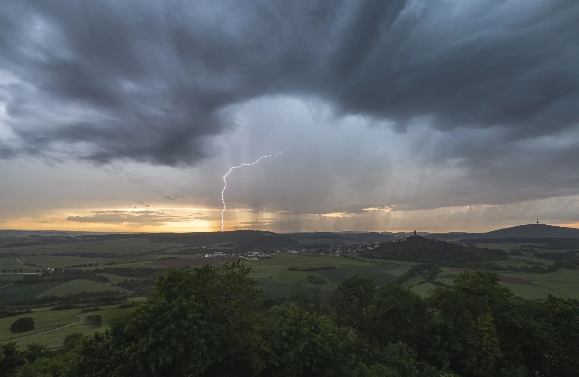 Gewitterzelle mit Blitz über weiten Feldern