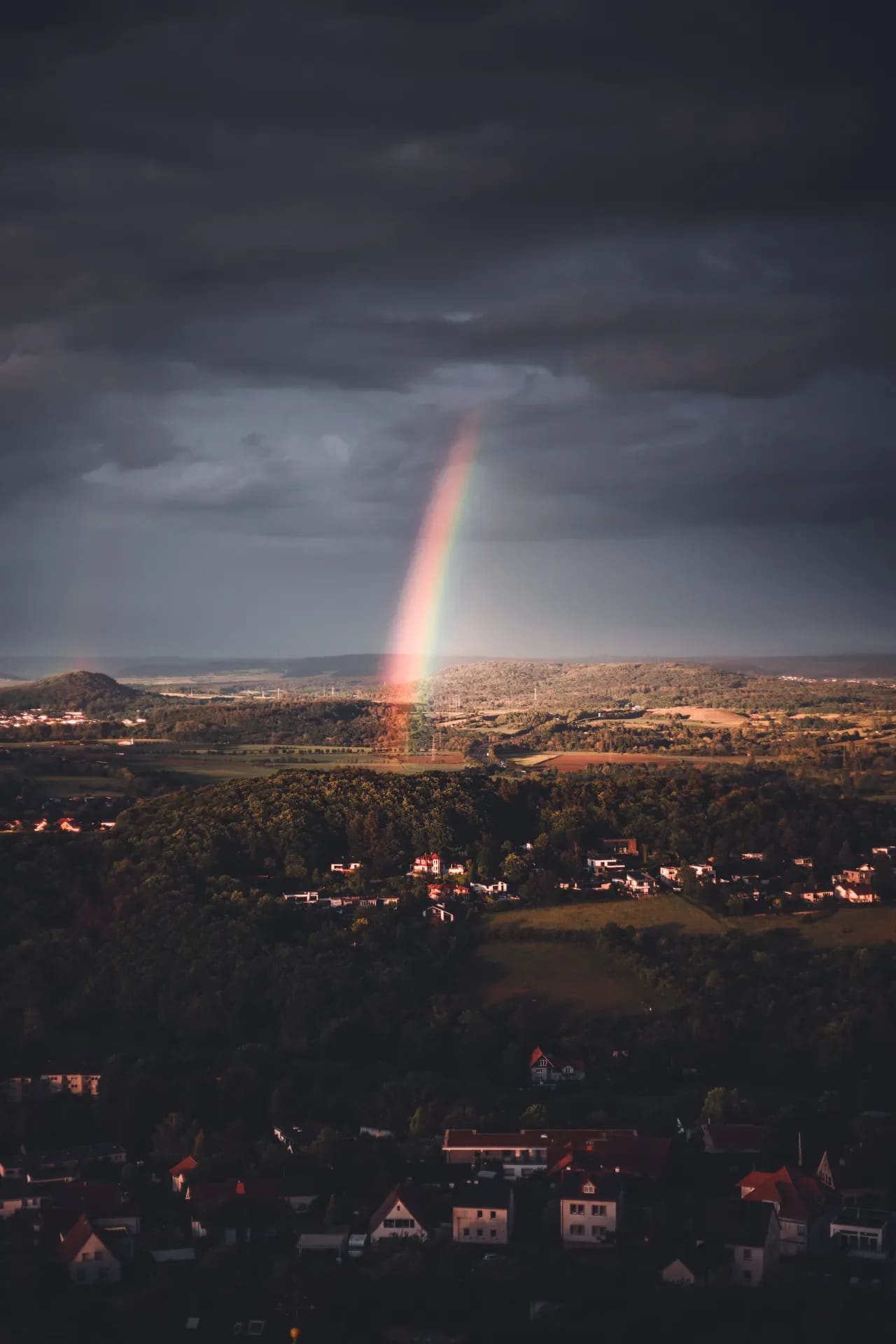 Regenbogen über der Stadt unter dunklen Wolken
