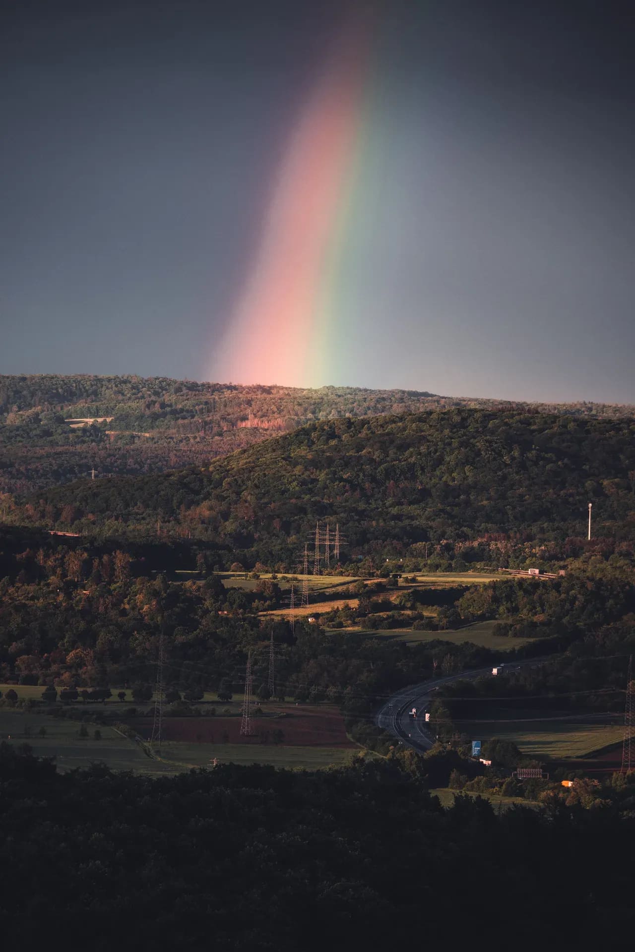 Regenbogen über einem bewaldeten Hang